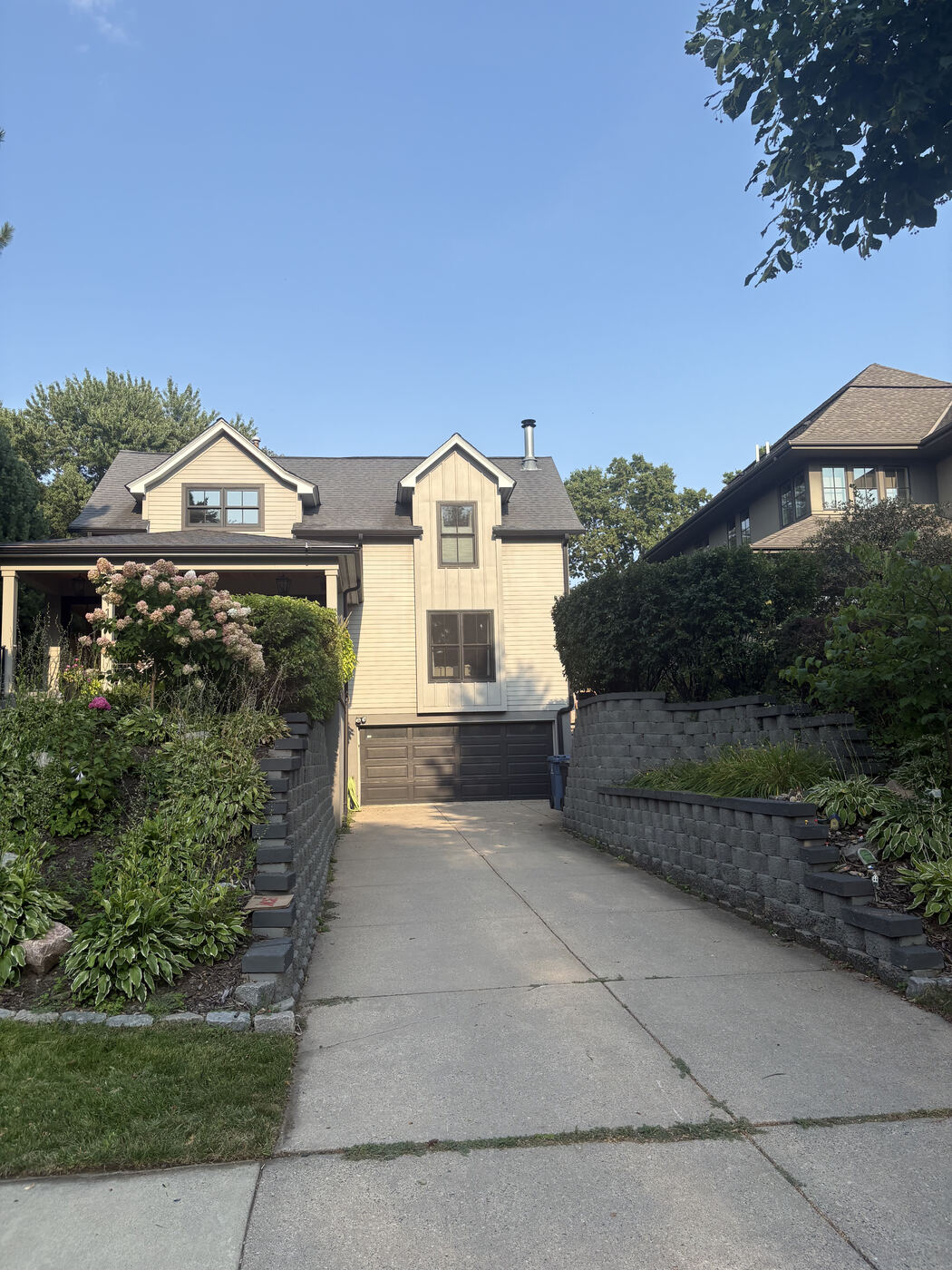 After: the same shrubs trimmed and shaped, with the walls and driveway visible again
