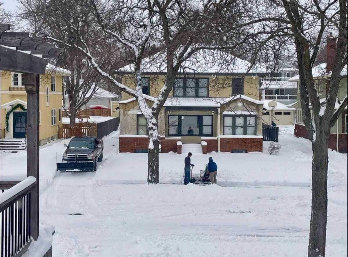 Crew clearing deep snow from a Minneapolis driveway with a plow truck